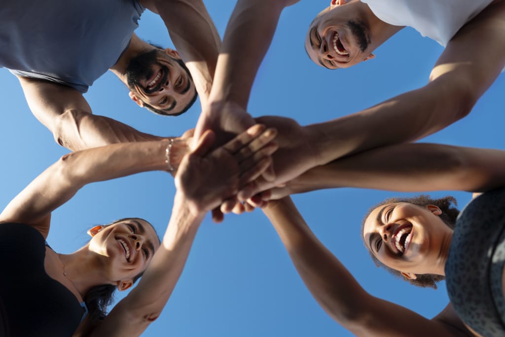 group-people-putting-their-hands-together-while-exercising-outdoors-scaled